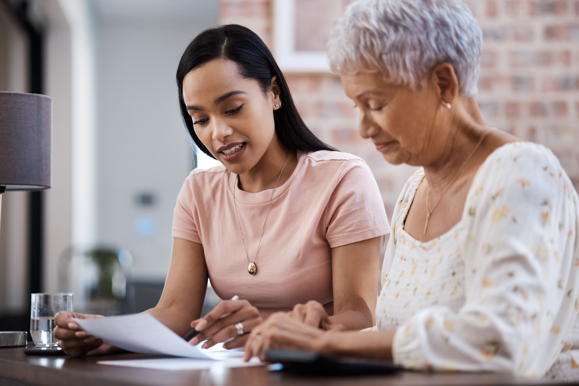 Shot of a young woman going over paperwork with her elderly mother at home