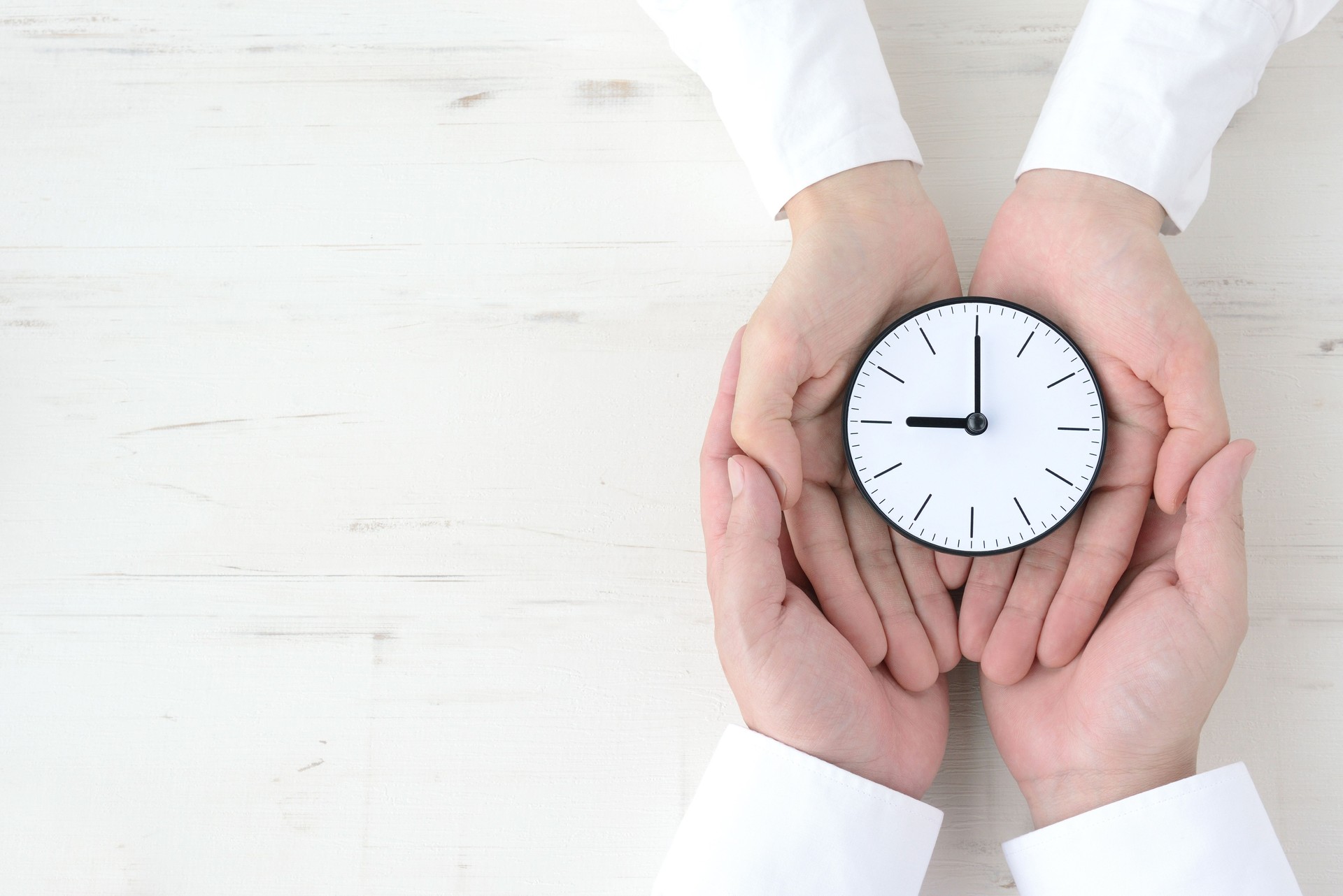 Couple's hands with watch on natural wooden board